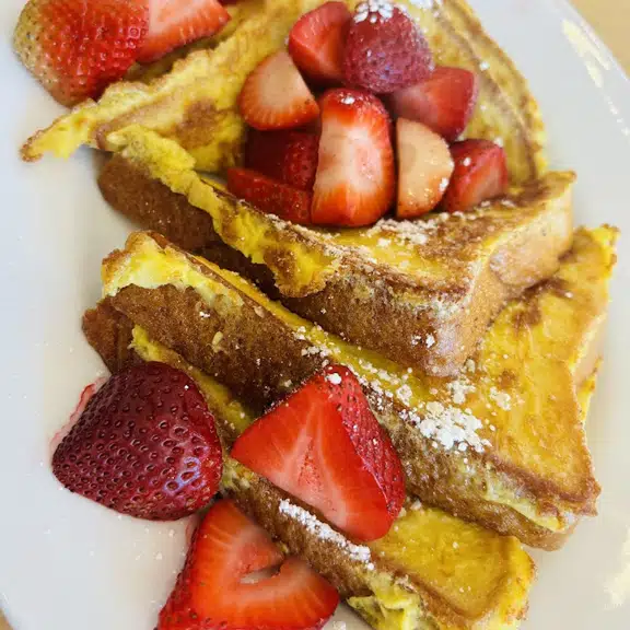 French toast topped with fresh strawberries and powdered sugar