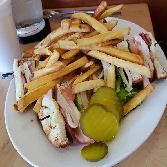 Club sandwich with fries and pickle on side